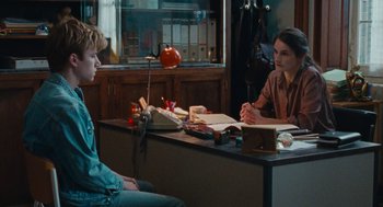 Movie still from “Summer of 85” (2020), directed by François Ozon – Two people sitting at a table in front of a typewriter; Medium shot, Over the shoulder angle