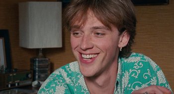 Movie still from “Summer of 85” (2020), directed by François Ozon – A young man smiles brightly while wearing a green shirt; Close Up shot, Over the shoulder angle