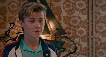 Movie still from “Summer of 85” (2020), directed by François Ozon – A young man standing in front of a floral wallpaper; Close Up shot, Over the shoulder angle