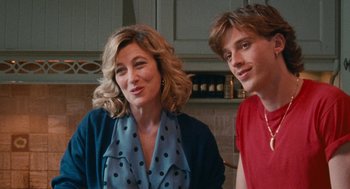 Movie still from “Summer of 85” (2020), directed by François Ozon – A woman sitting next to a young man in a kitchen; Close Up shot, Over the shoulder angle