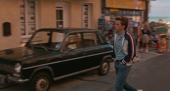 Movie still from “Summer of 85” (2020), directed by François Ozon – A man walking down a street past a black car; Wide shot, Low angle