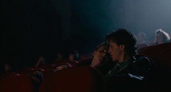 Movie still from “Summer of 85” (2020), directed by François Ozon – Two young men sitting in a movie theater; Medium shot, Low angle