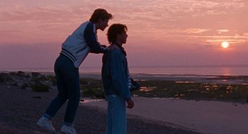 Movie still from “Summer of 85” (2020), directed by François Ozon – Two people standing on the beach at sunset; Wide shot, Over the shoulder angle