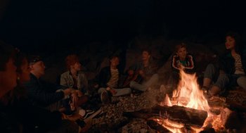 Movie still from “Summer of 85” (2020), directed by François Ozon – A group of people sitting next to a fire; Wide shot, High angle