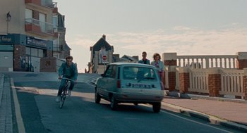 Movie still from “Summer of 85” (2020), directed by François Ozon – A group of people riding bikes down a street; Extreme Wide shot, High angle