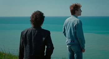 Movie still from “Summer of 85” (2020), directed by François Ozon – Two men standing on a cliff overlooking the ocean; Medium shot, Over the shoulder angle