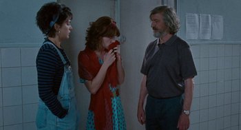 Movie still from “Summer of 85” (2020), directed by François Ozon – Three people are standing in a room and one person is holding an object in her mouth; Medium shot, Over the shoulder angle