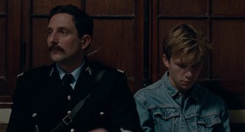 Movie still from “Summer of 85” (2020), directed by François Ozon – Two men sitting next to each other in front of a wooden wall; Close Up shot, Over the shoulder angle