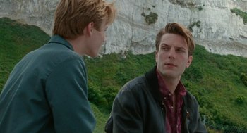 Movie still from “Summer of 85” (2020), directed by François Ozon – Two young men are standing in front of a cliff; Close Up shot, Over the shoulder angle