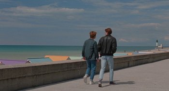 Movie still from “Summer of 85” (2020), directed by François Ozon – Two young men are walking along the boardwalk; Wide shot, High angle