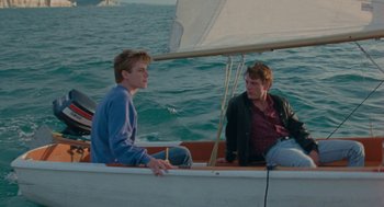 Movie still from “Summer of 85” (2020), directed by François Ozon – Two men sitting on a boat in the water; Medium shot, High angle