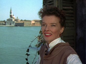 Movie still from “Summertime” (1955), directed by David Lean – A person smiling near a body of water; Close Up shot, Low angle