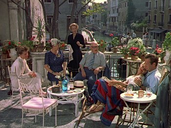Movie still from “Summertime” (1955), directed by David Lean – A group of people sitting at a table with drinks; Wide shot, High angle