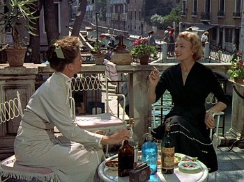 Movie still from “Summertime” (1955), directed by David Lean – Two women are sitting at a table and talking to each other; Wide shot, High angle