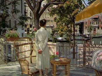Movie still from “Summertime” (1955), directed by David Lean – A woman in a bathrobe standing on a balcony; Wide shot, High angle