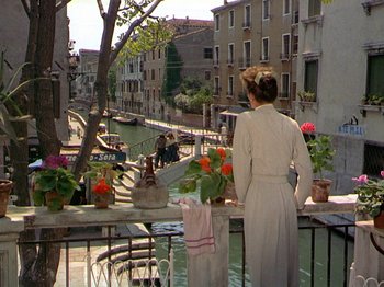 Movie still from “Summertime” (1955), directed by David Lean – A woman standing on a balcony looking out over a canal; Wide shot, High angle