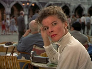 Movie still from “Summertime” (1955), directed by David Lean – A woman sitting at an outdoor table in a restaurant; Close Up shot, Low angle