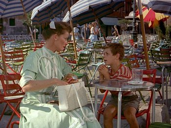 Movie still from “Summertime” (1955), directed by David Lean – A woman and a child sitting at a table; Medium shot, Over the shoulder angle