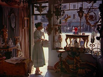 Movie still from “Summertime” (1955), directed by David Lean – A woman standing in front of a window in a store; Wide shot, High angle