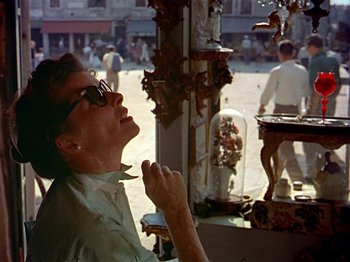 Movie still from “Summertime” (1955), directed by David Lean – An older woman is looking out a window at a market place; Medium shot, Low angle