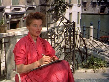 Movie still from “Summertime” (1955), directed by David Lean – An older woman sitting on a bench writing on a piece of paper; Medium shot, Low angle