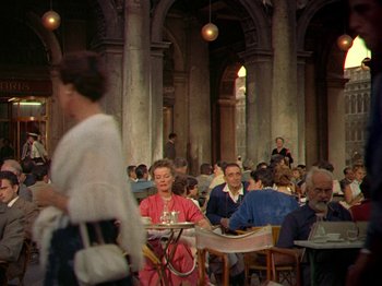 Movie still from “Summertime” (1955), directed by David Lean – A group of people sitting at tables in a restaurant; Wide shot, High angle