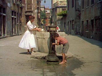 Movie still from “Summertime” (1955), directed by David Lean – A woman and a boy playing with a water fountain; Wide shot, High angle