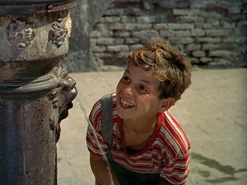 Movie still from “Summertime” (1955), directed by David Lean – A young boy is playing with a water fountain; Medium shot, High angle