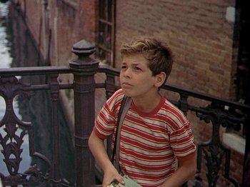 Movie still from “Summertime” (1955), directed by David Lean – A young boy is sitting on a railing outside; Medium shot, High angle