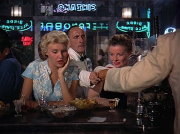 Movie still from “Summertime” (1955), directed by David Lean – Two women and a man sitting at a table in front of a bowl; Medium shot, Over the shoulder angle