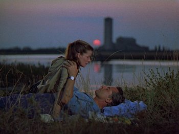 Movie still from “Summertime” (1955), directed by David Lean – A man and a woman laying in the grass at night; Medium shot, Low angle