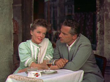 Movie still from “Summertime” (1955), directed by David Lean – A man and a woman sitting at a table with a glass of wine; Medium shot, Over the shoulder angle