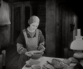 Movie still from “Sunrise” (1927), directed by F.W. Murnau – An old photo of a woman preparing a meal; Medium shot, High angle