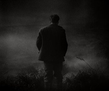 Movie still from “Sunrise” (1927), directed by F.W. Murnau – A man standing in a field in the fog; Medium shot, Low angle