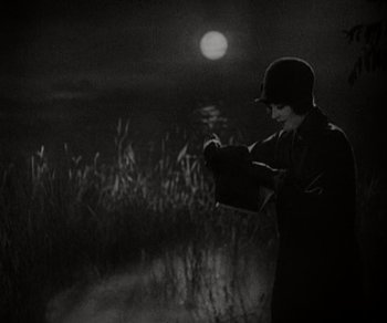 Movie still from “Sunrise” (1927), directed by F.W. Murnau – A man standing in a field at night holding a gun; Medium shot, Low angle