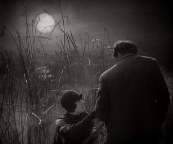 Movie still from “Sunrise” (1927), directed by F.W. Murnau – A man and a woman standing next to each other in a field at night; Medium shot, High angle