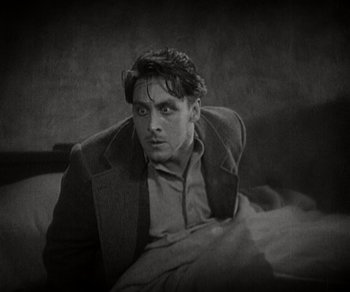 Movie still from “Sunrise” (1927), directed by F.W. Murnau – A black and white photo of a man sitting on a couch; Medium shot, High angle