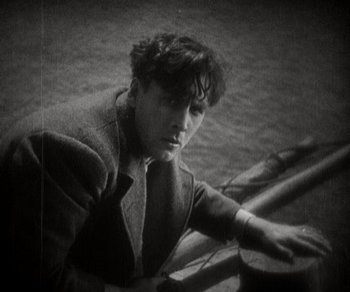 Movie still from “Sunrise” (1927), directed by F.W. Murnau – A man leaning on a railing in an old photo; Close Up shot, High angle