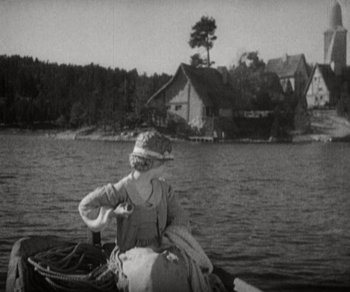 Movie still from “Sunrise” (1927), directed by F.W. Murnau – A woman sitting on a boat in the water; Wide shot, High angle