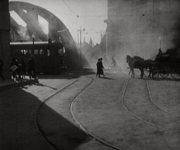 Movie still from “Sunrise” (1927), directed by F.W. Murnau – A black and white photo of a train station with people on the tracks; Extreme Wide shot, High angle