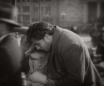 Movie still from “Sunrise” (1927), directed by F.W. Murnau – A man and a woman hugging in a room; Medium shot, High angle