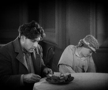 Movie still from “Sunrise” (1927), directed by F.W. Murnau – A man and a woman sitting at a dinner table; Medium shot, High angle