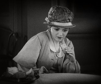 Movie still from “Sunrise” (1927), directed by F.W. Murnau – A woman sitting at a table with a plate of food in front of her; Medium shot, High angle