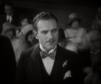 Movie still from “Sunrise” (1927), directed by F.W. Murnau – A black and white photo of a man in a suit and bow tie; Close Up shot, High angle