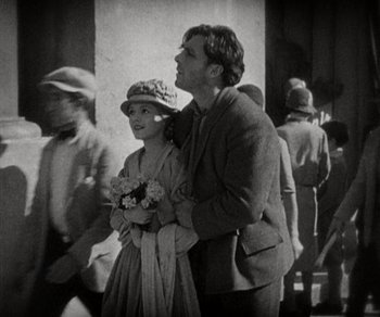 Movie still from “Sunrise” (1927), directed by F.W. Murnau – A man and a woman standing next to each other on the street; Medium shot, High angle