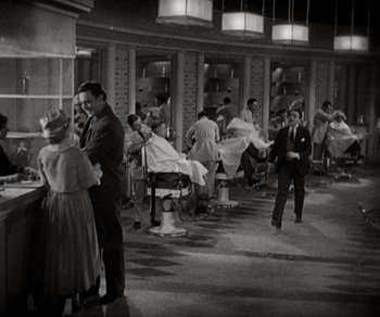 Movie still from “Sunrise” (1927), directed by F.W. Murnau – A black and white photo of people in a barber shop; Wide shot, High angle