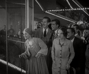 Movie still from “Sunrise” (1927), directed by F.W. Murnau – A black and white photo of a group of people; Wide shot, High angle