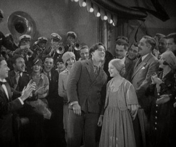 Movie still from “Sunrise” (1927), directed by F.W. Murnau – A group of people standing in front of a microphone; Wide shot, High angle