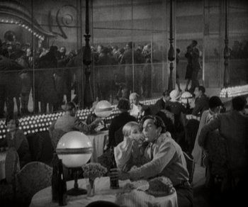 Movie still from “Sunrise” (1927), directed by F.W. Murnau – A black and white photo of people sitting at a table; Wide shot, High angle