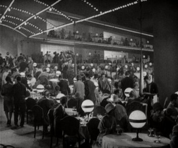 Movie still from “Sunrise” (1927), directed by F.W. Murnau – A group of people sitting at tables in a room; Extreme Wide shot, High angle